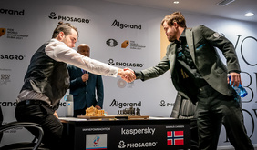 Foto von der Schach-WM. Zu sehen ist Magnus Carlsen, der sich stehend über das Brett beugt und seinen sitzenden Herausforderer, Jan Nepomnjaschtschi, mit einem Handschlag begrüßt.