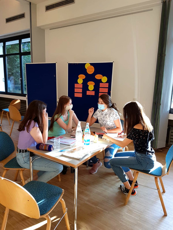 4 Personen sitzen um einen Tisch und diskutieren